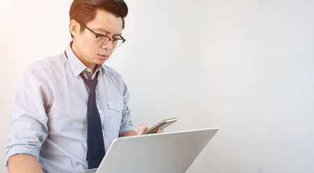 Asian business men working with laptop computers and holding mobile phones on a white background.の写真素材