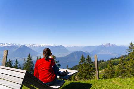 a woman chill out and enjoy a beautiful view of the snow mountain from the top of Riki Kulmの写真素材