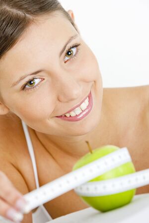 portrait of young woman with green apple and tape measureの写真素材
