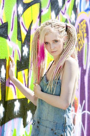 portrait of young woman standing at graffitti wallの写真素材
