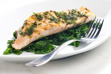 grilled salmon with herbs on fried spinachの写真素材
