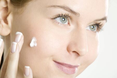portrait of woman putting cream on faceの写真素材