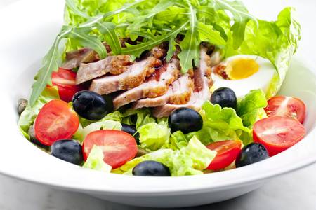 vegetable salad with fried duck breast slices and eggの写真素材