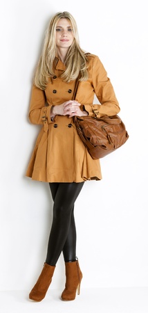 standing woman wearing coat and fashionable brown shoes with a handbagの写真素材