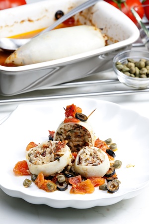 baked sepia with tomatoes and black olives filled with pearl barley risottoの写真素材