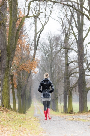 woman wearing rubber boots in autumnal alleyの写真素材