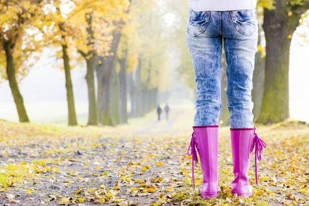 detail of woman wearing rubber boots in autumnal alleyの写真素材