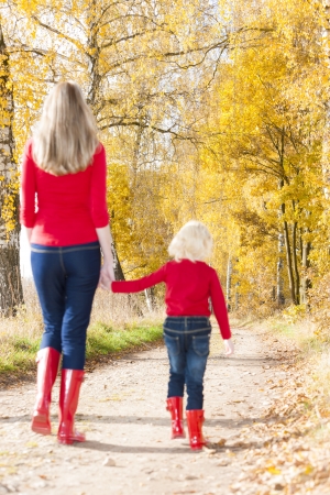 mother with her daughter in autumnal alleyの写真素材