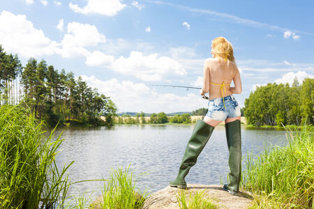 young woman fishing at pond in summerの写真素材