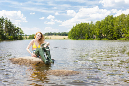 young woman fishing in pond during summer
