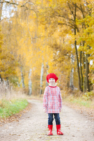 little girl wearing rubber boots in autumnal alleyの写真素材