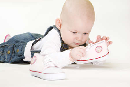 lying down baby girl holding shoesの写真素材