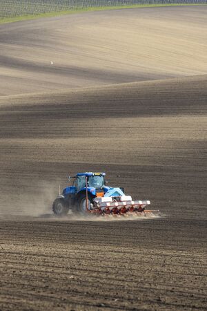 Tractor with seed drill in early spring landscape