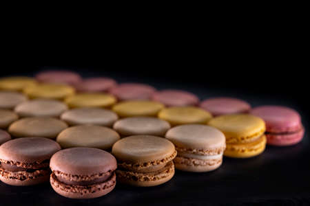 chocolate, coffee, vanilla, lemon and strawberry macaroons on black background
