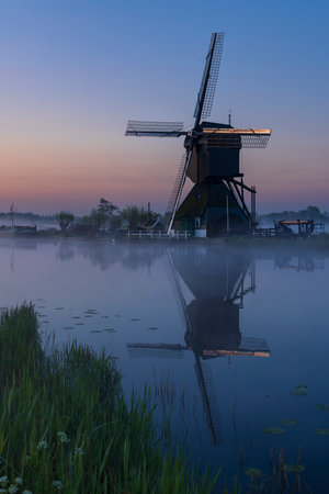 Traditional Dutch windmills with a colourful sky just before sunrise in Kinderdijk, The Netherlandsの写真素材