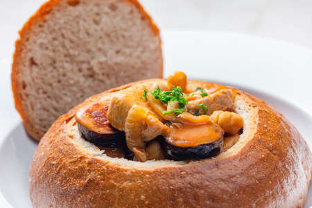 stew with pork meat, chickpeas and sausge in loaf of bread