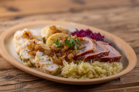 smoked meat served with red and white cabbage and two kinds of dumplingsの写真素材