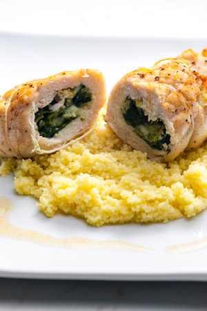 poultry roulade filled with spinach and cheese served with couscousの写真素材