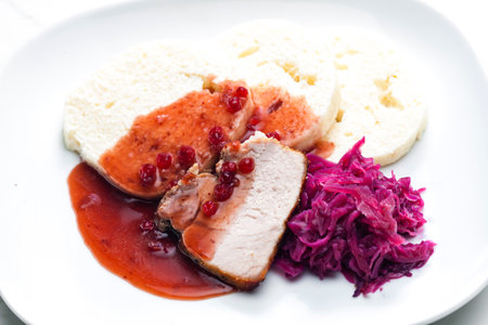 pork meat with red cabbage, cranberry sauce and dumplingsの写真素材