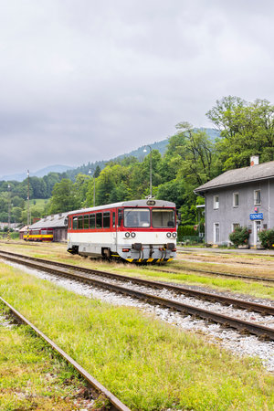 Red and white diesel railcar waiting at the station in Tisovec, Slovakia, on a cloudy summer dayの写真素材