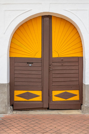 Brown double door with yellow sun like decorations in the upper part and rhombus shaped at the bottom in Stare Mesto pod Landstejnem, Czechiaの写真素材