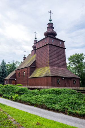Traditional wooden orthodox church of Saint Michael Archangel in Brunary, Poland, featuring three towers and crosses, surrounded by lush greeneryの写真素材