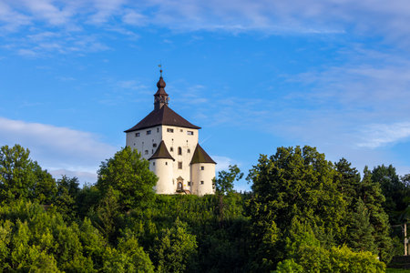 The New Castle in Banska Stiavnica, Slovakia, stands majestically on a hill, surrounded by lush greenery under a vibrant blue skyの写真素材