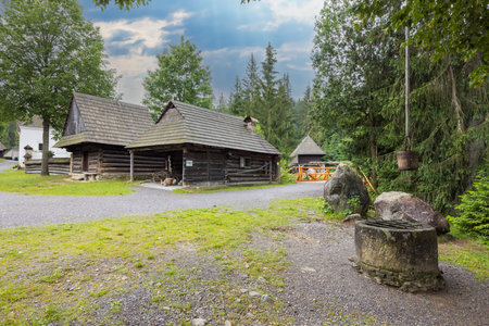 Traditional wooden houses and stone water well are displayed at the Museum of the Orava Village in Zuberec, Slovakiaの写真素材