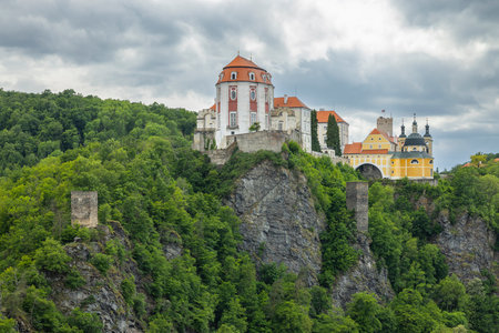 Vranov nad Dyji Chateau standing on a cliff in Czechia, surrounded by lush green vegetation, under a cloudy skyの写真素材