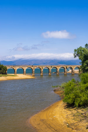 Panoramic view of the old stone bridge over the Ebro reservoir in Arija, Burgos, Spain, on a sunny summer dayの写真素材