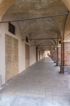 Empty arcades with decorated doors and brick columns in Via Baldassarre della Mantica, Cherasco, Piedmont, Italyの写真素材