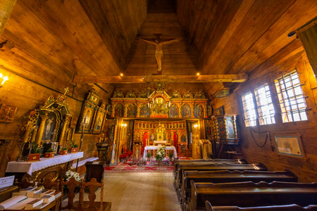 Traditional wooden church interior with altar, benches, and religious icons in Powroznik, Lesser Poland Voivodeshipの写真素材