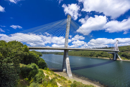 Modern cable stayed bridge crossing Aulne river near Argol, Finistere, under blue sky with white cloudsの写真素材