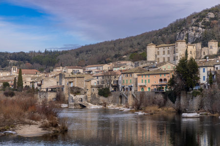 Panoramic view of Vogue village reflecting on the Ardeche river in winter, with its medieval castle and stone housesの写真素材