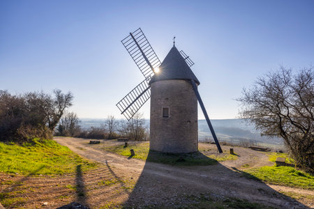Sun shining behind a traditional windmill in Santenay, Bourgogne Franche Comte, Franceの写真素材