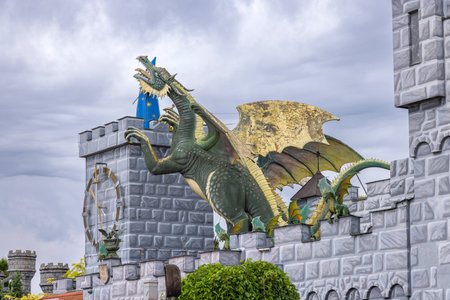 Green and yellow dragon statue climbing the wall of a castle with a clock tower in Chvalovice, Czechiaの写真素材
