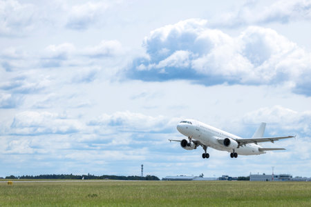 White passenger airplane taking off over green field from runway at Airport Prague in Hostivice, Czechiaの写真素材