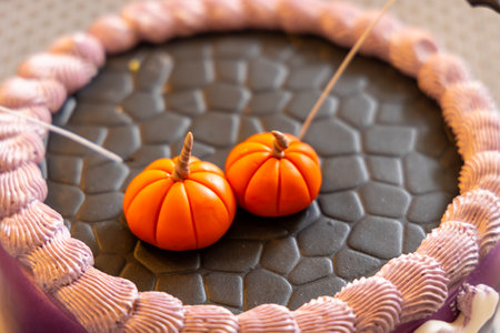 Two orange sugar pumpkins decorating a halloween cake with cobblestone pattern and purple icingの写真素材