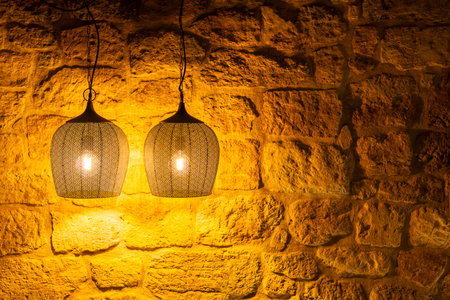 Two vintage metal lamps hanging and illuminating a stone wall, creating a warm and inviting atmosphere in Gnas, Styria, Austriaの写真素材