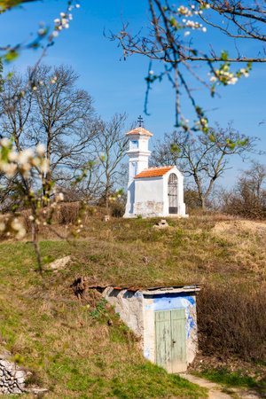 White chapel standing on a hill in Brod nad Dyji, Czechia, overlooking a cellar during a sunny spring dayの写真素材