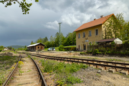 Old train station building with rusty rails and cloudy sky in Ustek, Czechia, showing the passage of time and the beauty of decayの写真素材