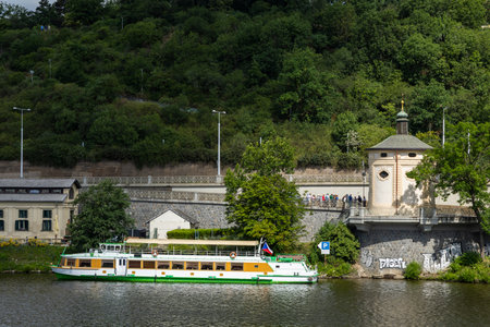 Riverboat cruising near lush greenery and historical architecture in Pragueの写真素材