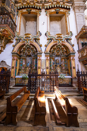 Sunlight streams onto wooden pews inside a richly decorated Portuguese churchの写真素材