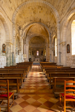 Ancient stone church featuring vaulted ceilings, wooden pews and checkerboard floor in Montagne, Franceの写真素材