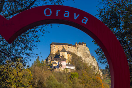 Orava Castle beautifully framed by a red arch under a clear blue skyの写真素材