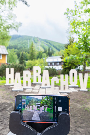 Smartphone photographing Harrachov sign with scenic backdropの写真素材