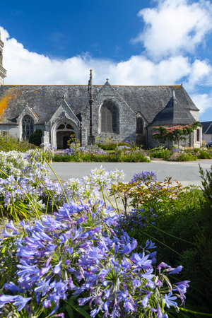 Stone church surrounded by vibrant flowers under a bright blue skyの写真素材
