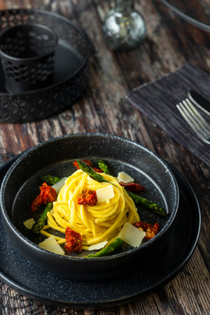 Elegant pasta dish with cheese and colorful garnishes on rustic tableの写真素材
