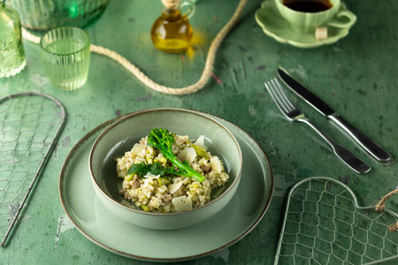 Delicious mushroom risotto garnished with greens on a rustic green tableの写真素材