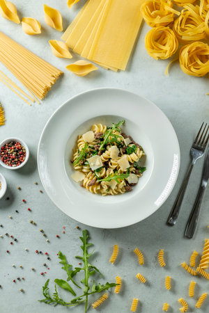Tasty pasta served with arugula and cheese on a white plateの写真素材